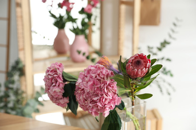 Vase with fresh beautiful flowers in florist's workshop