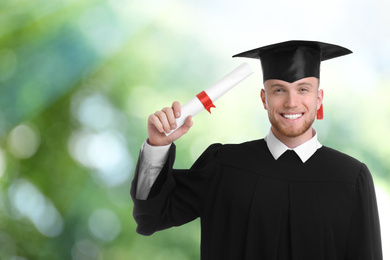 Happy student with graduation hat and diploma on blurred background, space for text