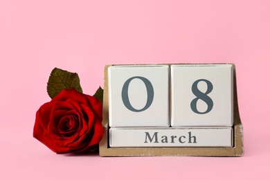 Wooden block calendar with date 8th of March and rose on pink background, space for text. International Women's Day
