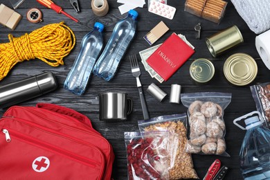 Disaster supply kit for earthquake on black wooden table, flat lay