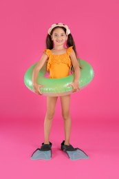 Cute little child in beachwear with bright inflatable ring on pink background