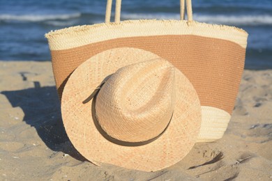 Stylish bag and hat near sea on sunny day, closeup. Beach accessories