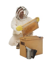 Beekeeper in uniform taking frame with honeycomb out of wooden hive on white background