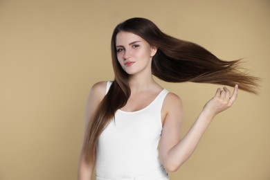 Young woman with strong healthy hair on beige background