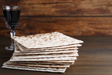 Stack of matzos and red wine on wooden table. Space for text