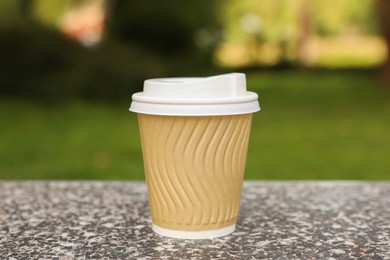 Paper cup on parapet in park, closeup. Coffee to go