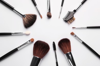 Frame of makeup brushes on white background, flat lay
