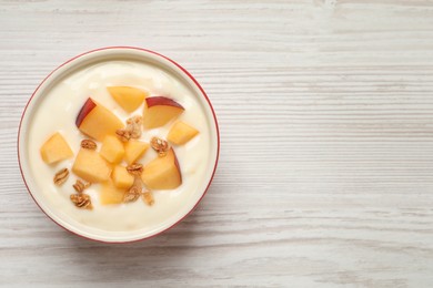 Delicious yogurt with fresh peach and granola on white wooden table, top view. Space for text