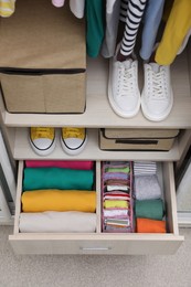 Wardrobe with organized clothes and shoes indoors, above view. Vertical storage