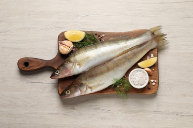 Fresh raw pike perches and ingredients on light wooden table, top view. River fish