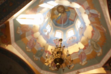 Photo of Blurred view of beautiful church interior with dome vault and chandelier