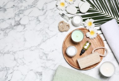 Flat lay composition with spa essentials on white marble background. Space for text