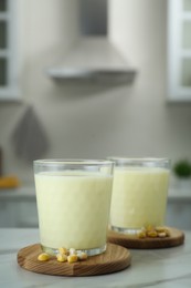 Tasty fresh corn milk in glasses on white table indoors, space for text