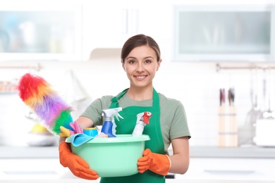 Woman in uniform with cleaning supplies indoors