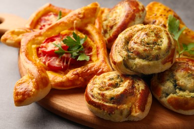 Photo of Different delicious puff pastry with tasty filling on wooden board, closeup