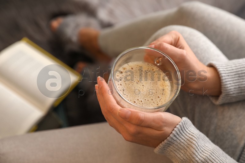 Woman with cup of hot coffee resting at home, above view