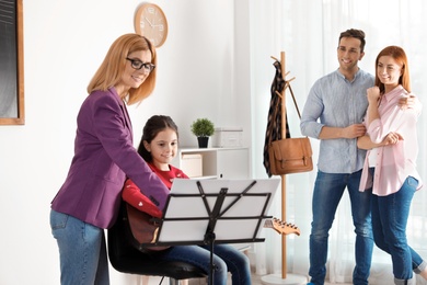 Little girl with her teacher and parents at music lesson. Learning notes