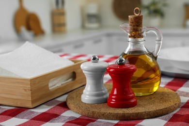 Ceramic salt and pepper mills with bottle of oil on kitchen table