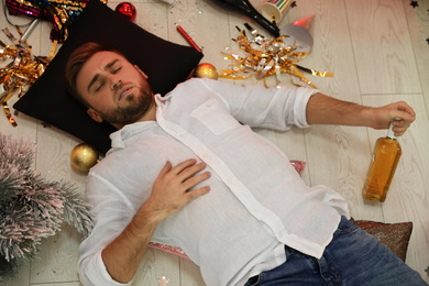 Drunk man sleeping on floor in messy room after New Year party, above view