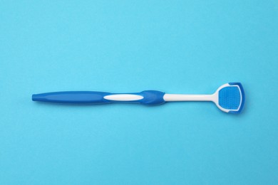 Tongue cleaner on light blue background, top view