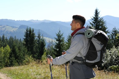 Tourist with backpack and trekking poles enjoying mountain landscape