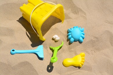 Bright plastic bucket, rake and shovel on sand. Beach toys