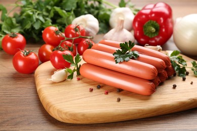Fresh raw vegetarian sausages with parsley and vegetables on wooden table