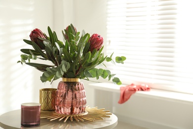 Photo of Vase with bouquet of beautiful Protea flowers on table in room
