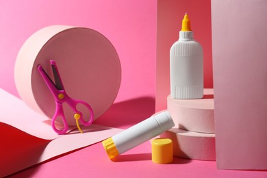 Composition with glue, paper and scissors on pink background