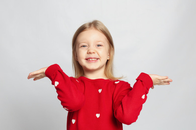 Portrait of cute funny little girl on light grey background