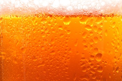 Photo of Glass of tasty cold beer with foam and condensation drops as background, closeup