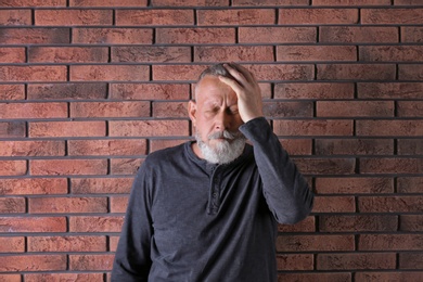 Senior man in state of depression near brick wall