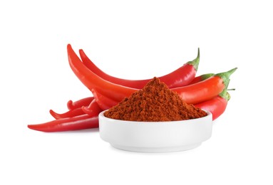 Fresh chili peppers and bowl of paprika powder on white background
