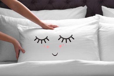 Woman plumping pillow with cute face in bedroom, closeup