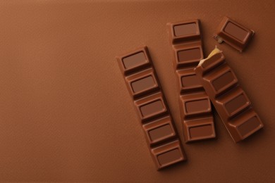 Photo of Delicious chocolate bars on brown background, flat lay. Space for text