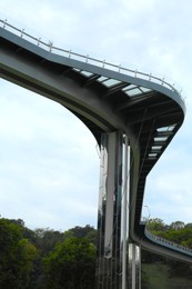 Photo of Beautiful pedestrian bridge with viewing platform against cloudy sky, low angle view