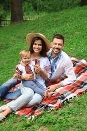 Happy family in Ukrainian national clothes on green grass outdoors