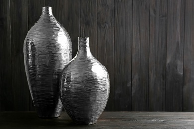 Stylish silver ceramic vases on black wooden table. Space for text