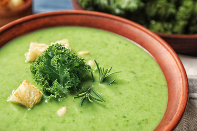 Tasty kale soup with croutons on table, closeup