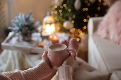 Photo of Woman holding cup of cocoa at home, closeup. Christmas mood