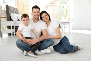 Happy parents and their son sitting together on floor at home. Family time
