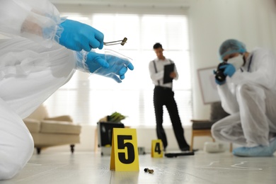 Investigators working at crime scene in messy room, closeup