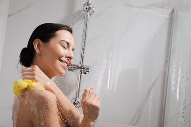 Young woman with mesh pouf taking shower at home. Space for text