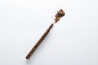Glass tube with ground chilli pepper on white background, top view