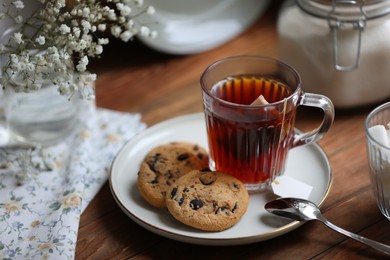 Cup of freshly brewed tea and delicious cookies on wooden table