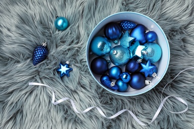 Beautiful Christmas baubles and box on grey faux fur, flat lay