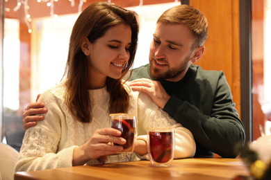 Couple with tasty mulled wine at table in cafe. Winter vacation