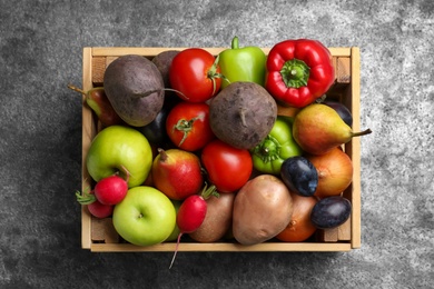 Wooden crate full of different vegetables and fruits on grey table, top view. Harvesting time