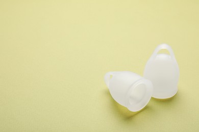 Menstrual cups on light green background. Space for text