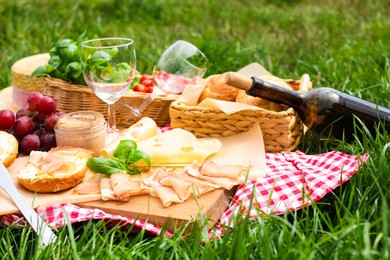 Picnic blanket with wine and food on green grass